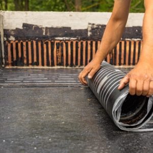 Worker laying the vapor barrier for the roof, bituminous membrane to be welded with flame